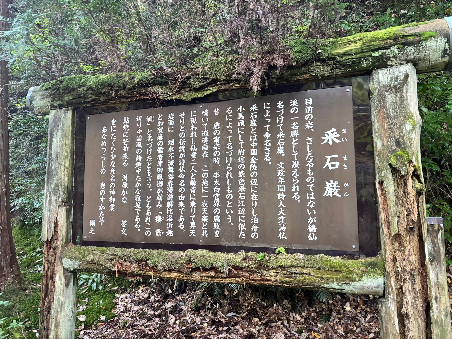 苔の付いた木枠に収められた采石巌の案内板